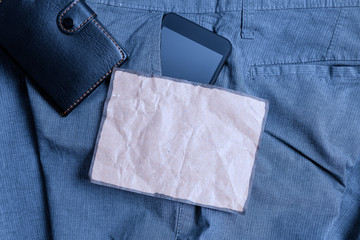 Smartphone device inside trousers front pocket with wallet and note paper