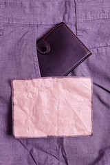 Small little wallet inside man trousers front pocket near notation paper