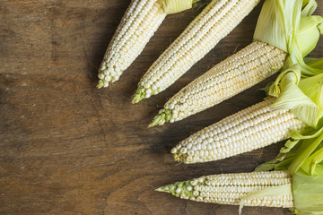 Fresh white corn cobs on old wooden background