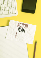 Text sign showing Action Plan. Business photo text detailed plan outlining actions needed to reach goals or vision Crumpled white paper on table with paper clips clock mobile and pc keyboard