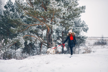 Cute girl in a winter park. Woman palying with a dog. Lady in a black jacket