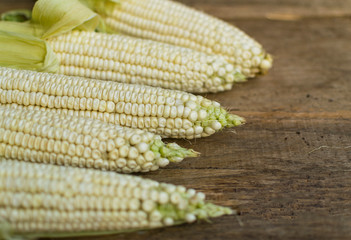 Fresh white corn cobs on old wooden background