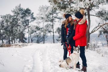 Fototapeta na wymiar Cute couple in a winter park. Woman palying with a dog. Lady in a black jacket