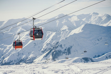 two large ski lifts in the sunny mountains transport people