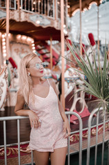 Beautiful hipster girl happy posing at the Ferris wheel near Agia Napa amusement park carousel