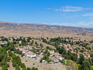 Fototapeta na wymiar Aerial view of small neighborhood with dry desert mountain on the background in Moorpark