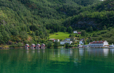 Fototapeta na wymiar A row of red small house with small boats at Flam, Norway. July 2019