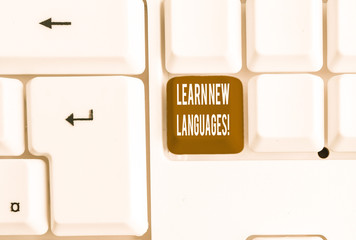 Writing note showing Learn New Languages. Business concept for developing ability to communicate in foreign lang White pc keyboard with note paper above the white background