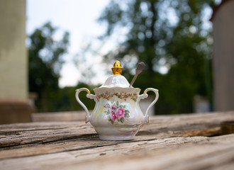 porcelain sugar bowl with a spoon on a table in the garden