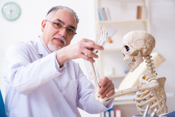 Aged male doctor with skeleton