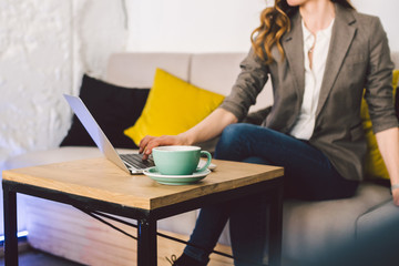 Closeup business woman hands using laptop with cup coffee. Woman Hands Typing keyboard computer In Coffee Shop. smartphone and hot cup Cappuccino in table. People lifestyles concept. Freelance theme