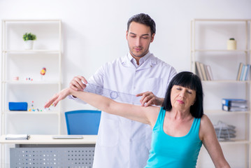 Obraz premium Young male doctor examining old female patient