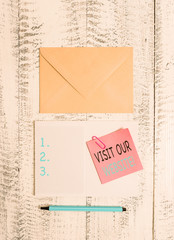 Writing note showing Visit Our Website. Business concept for visitor who arrives at web site and proceeds to browse Envelop squared notepad note clip marker old wooden vintage background