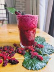 glass of mulberry​ smooth​ie on wooden table