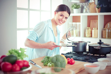 Young woman standing by the stove in the kitchen