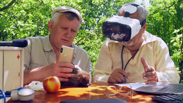 aged man in white sterile glove holds smartphone and magnifying glass over hedgehog. Concept virtual reality