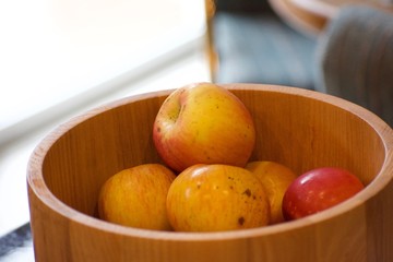 Red and yellow apples sitting in a wooden bowl