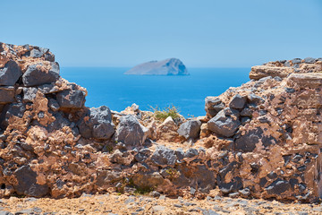 Fototapeta na wymiar Ruins of old historical wall with sea and island on a blurred background in Crete, Greece. 