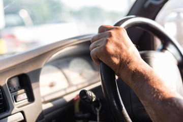 Men's hand holding the  steering wheel with sunlight