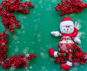 Smiling snowman toy in winter clothes, green red, white Christmas background with sorb bunches, snowflakes, template for greeting design with free space for text