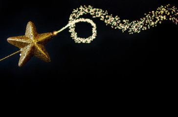 Christmas golden star magiс wand with fairy blowing dusty glitter curved line, isolated closeup on black background, template for border design with free space for text