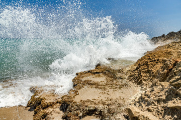 Ocean foamy waves at the beach near rocks, crystal clear turquoise water, Sosua, Puerto Plata, Dominican Republic