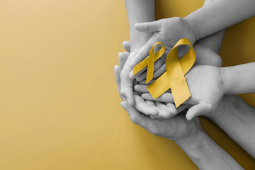 adult and children hands holding yellow gold ribbon, Sarcoma Awareness, Bone cancer, childhood...