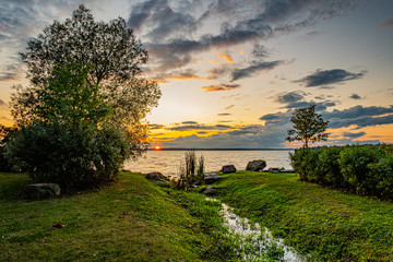 Sunset at Clardon Beach Georgina Ontario, with great view of the lake, trees, stones, clouds, and light