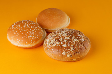 Rye and classic bun empty isolated. American food classic rye round burger bread isolated on orange background. Three different fried hamburger bun tops.