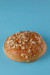 Rye bun empty isolated. American food classic rye round burger bread isolated on a blue background. Grilled burger bun top.
