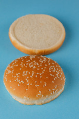 Burger bun empty isolated. American food classic round burger bread isolated on a blue background. Grilled burger bun top.