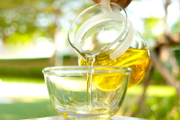 Pouring olive oil in the a glass bowl at stone kitchen and inside green garden view. Prepare for cooking concept. Healthcare and Beauty Concept.