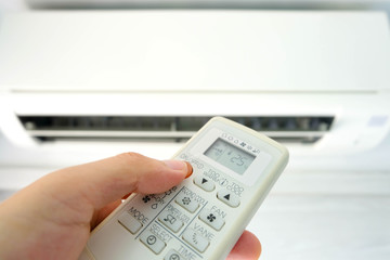 Man's hand using remote control open The air conditioner is cooled to 25 degrees Celsius in his bedroom. Health concepts and energy savings