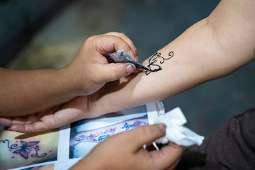 artist drawing butterfly on arm Henna paint