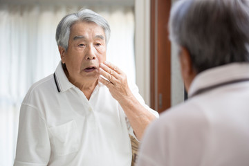 鏡を見る日本人のシニア男性