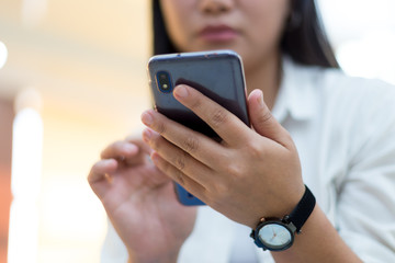 Female hand holds a smartphone. She uses a smartphone and sits in the office. Sexy girl