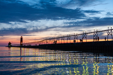 Grand Haven Lighthouse at sunset with catwalk lights reflected in Lake Michigan - obrazy, fototapety, plakaty