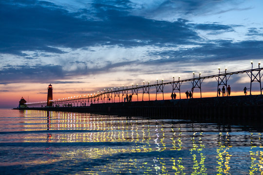 Grand Haven Lighthouse at sunset with catwalk lights reflected in Lake Michigan