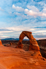 Delicate Arch with beautiful painting like clouds illuminated by sunset, Arches National Park, Utah