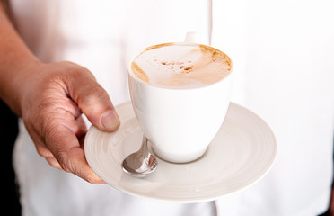 Cappuccino coffee cup with beautiful foam in woman hand