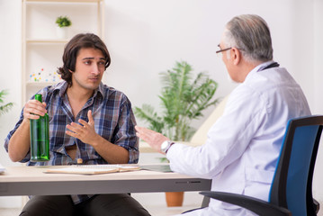 Fototapeta premium Young male alcoholic visiting old doctor