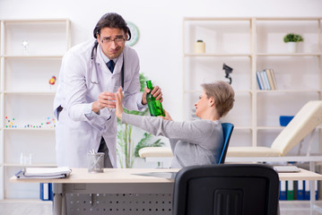 Obraz premium Female alcoholic visiting young male doctor