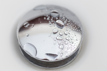 background, a drop of water on a shiny drain in the bathroom or on the sink close-up