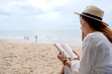 A beautiful woman sitting and reading book on the beach chair with feeling relaxed