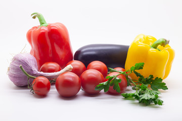 Vegetables, tomatoes, bell peppers, eggplant, garlic and parsley on a white background, selective focus