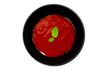 Tomato sauce in black bowl with mint leaves  isolated on white background.