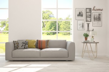Stylish room in white color with sofa and summer landscape in window. Scandinavian interior design. 3D illustration