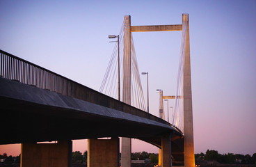 Cable suspension bridge over river at dusk