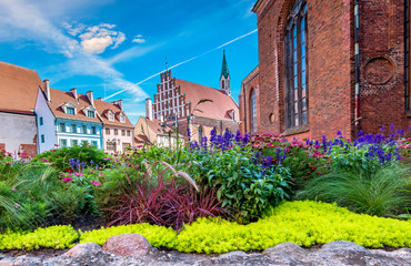 Fototapeta na wymiar Floral garden in front of St. John's Church that is the Evangelical Lutheran Church in old Riga. Riga is the capital of Latvia and famous tourist city in Baltic region, here tourists will able to feel