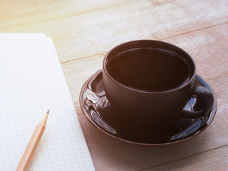  coffee cup and notebook for text on wooden table.